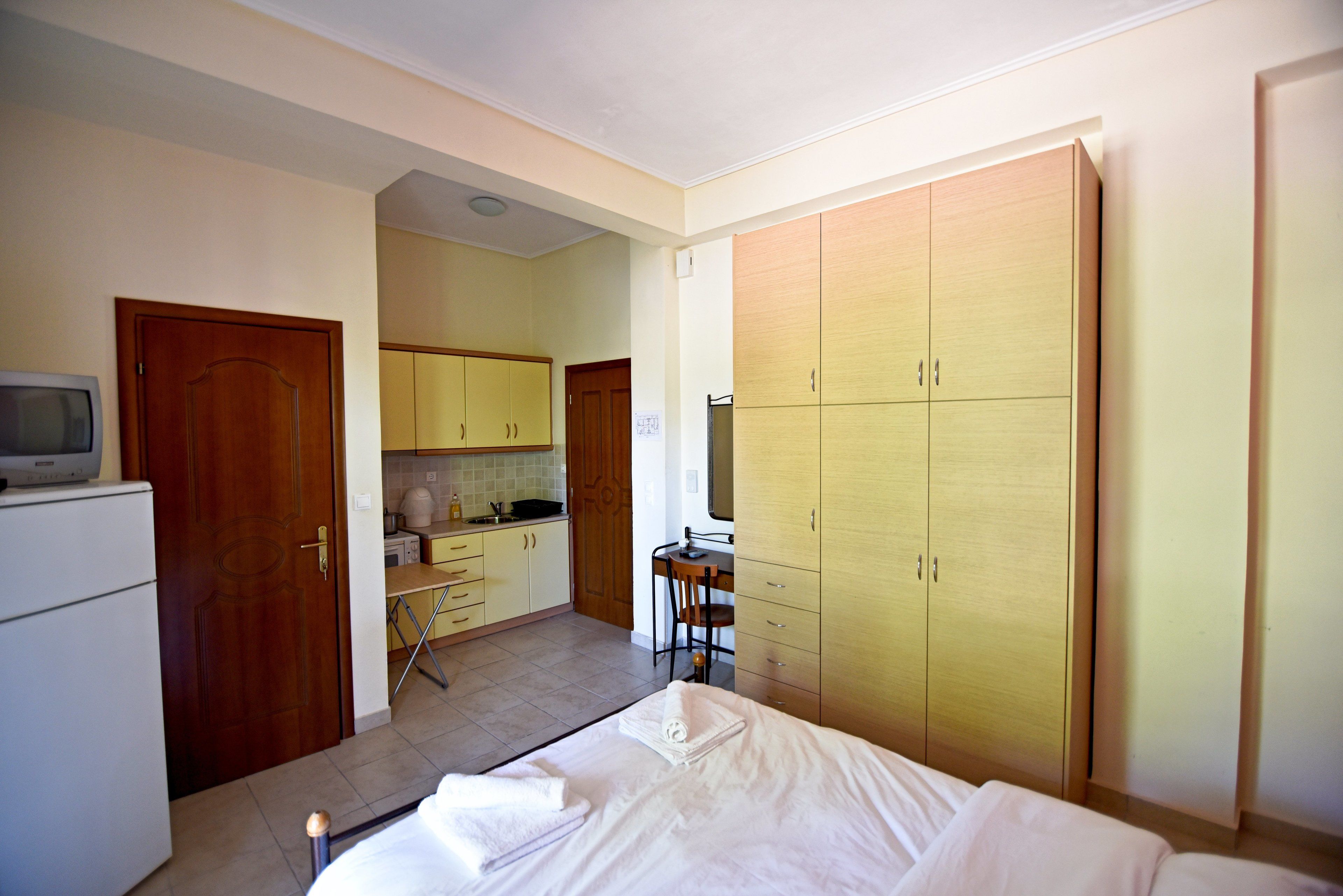 Une chambre avec un lit, un bureau et une kitchenette.
