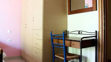 Une chambre avec une armoire en bois, un bureau avec une chaise et un miroir.