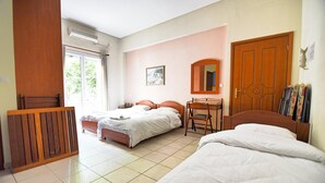Een hotelkamer met twee bedden, een houten bureau, een stoel, een spiegel en een raam met gordijnen.