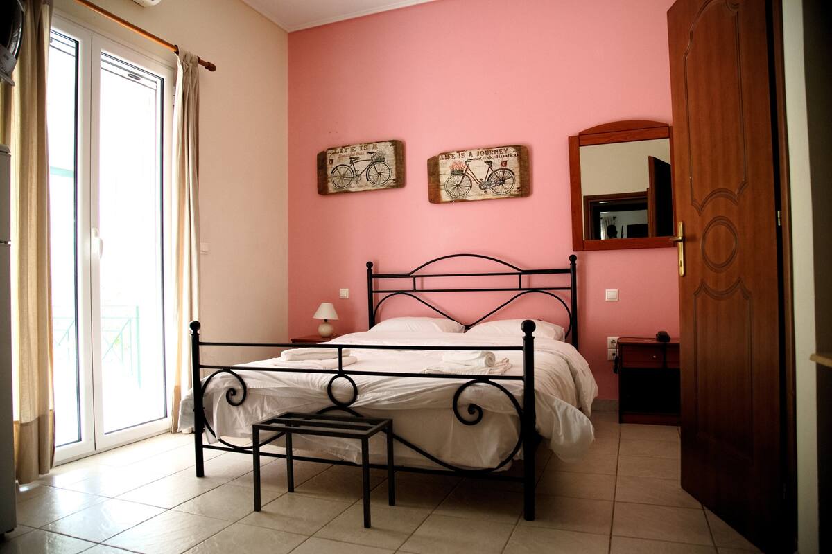 Een slaapkamer met een bed, een nachtkastje, een spiegel en twee decoraties aan de muur.