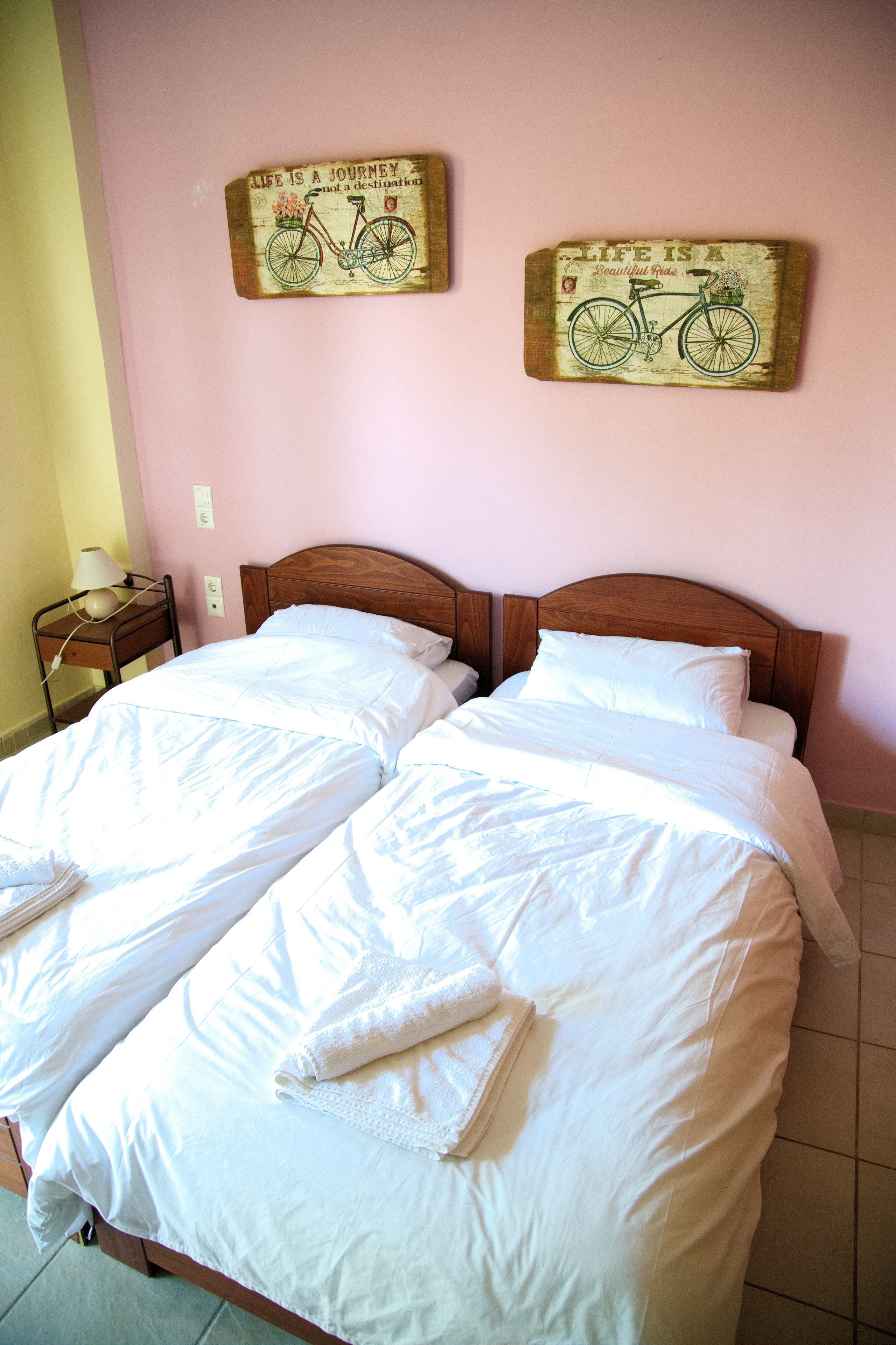 A double bed with white linens and two decorative wall pieces above it.