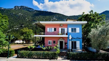Situated in a lush, green area, this two-story building offers a balcony with a view of the surrounding landscape and the distant mountains.