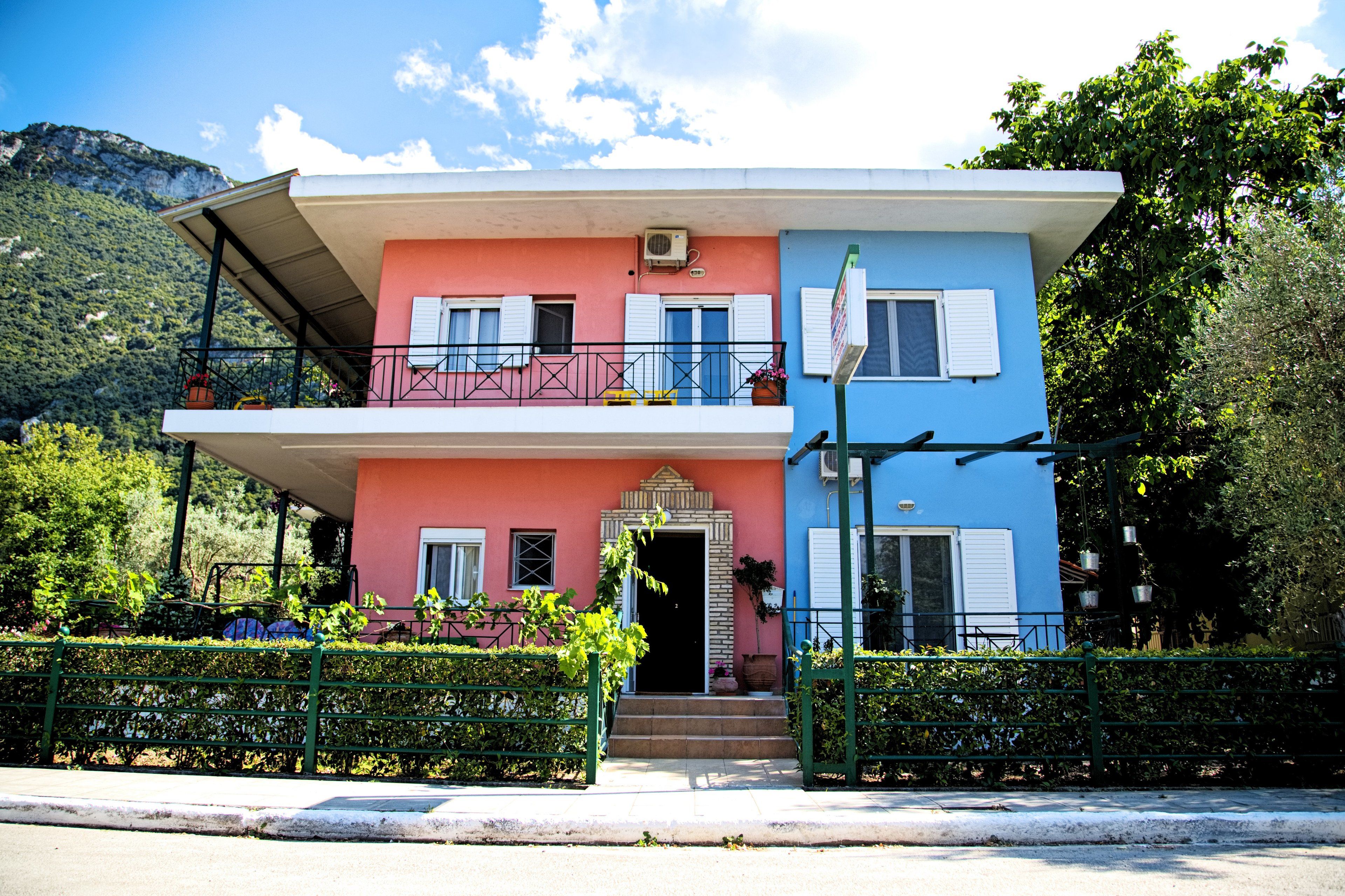 A two-story building with a balcony on the upper floor and a door with steps leading to the entrance.