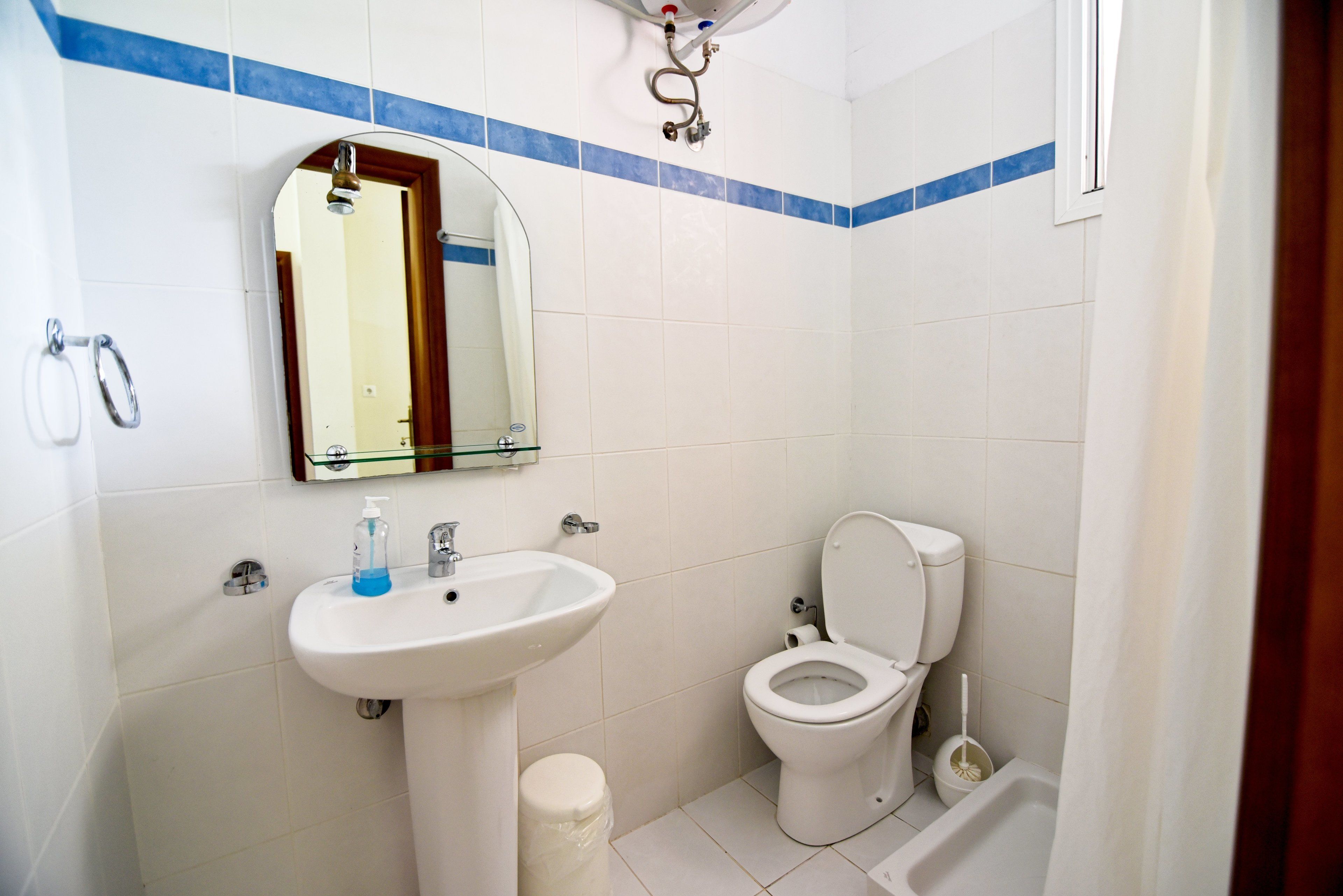 Une salle de bain avec un lavabo blanc, des toilettes et un espace douche.