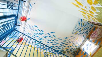Una escalera con un mural de peces en las paredes y un farol rojo colgado de la barandilla.