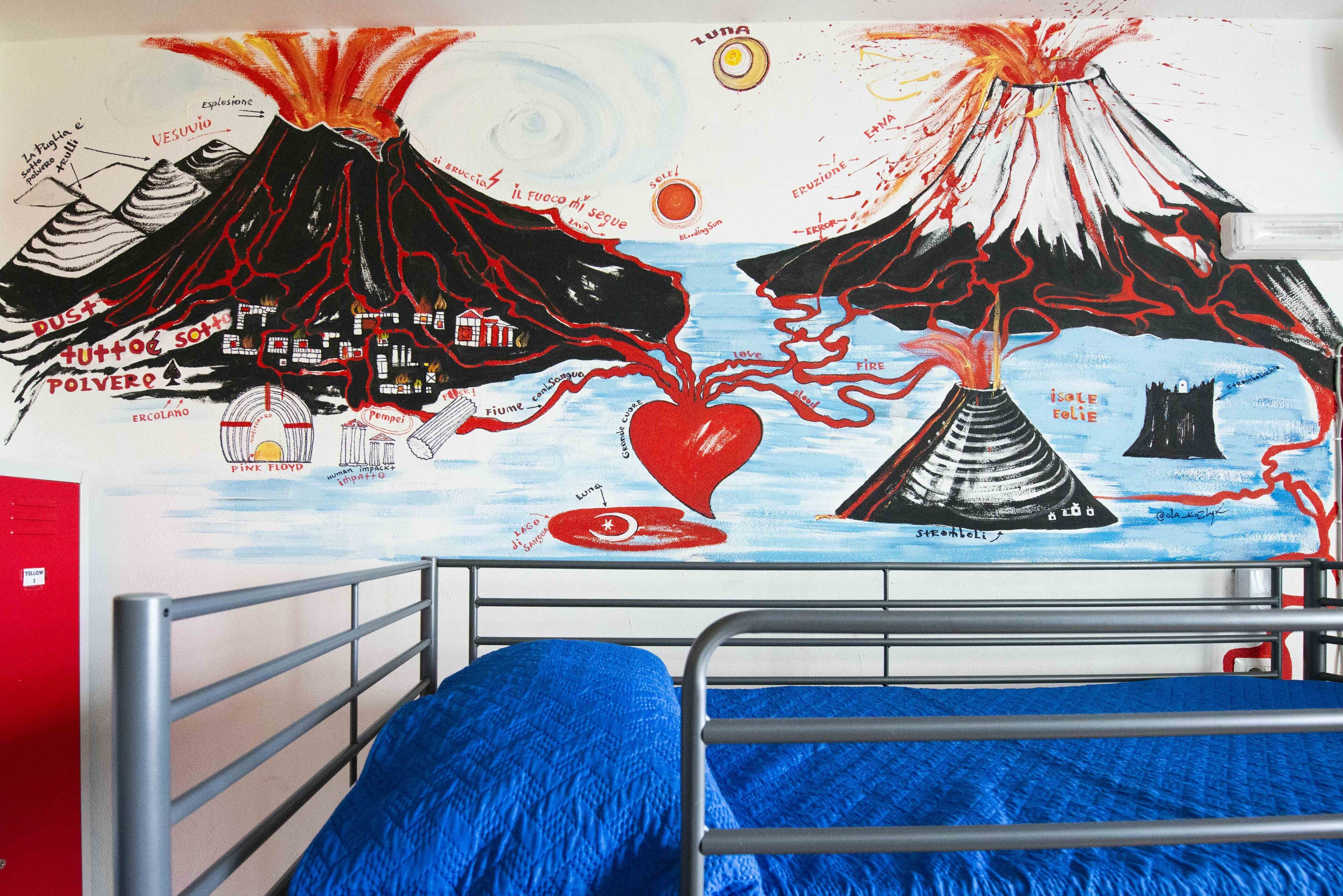 A bedroom with a metal bunk bed, a blue blanket, and a wall mural depicting volcanoes and a heart.