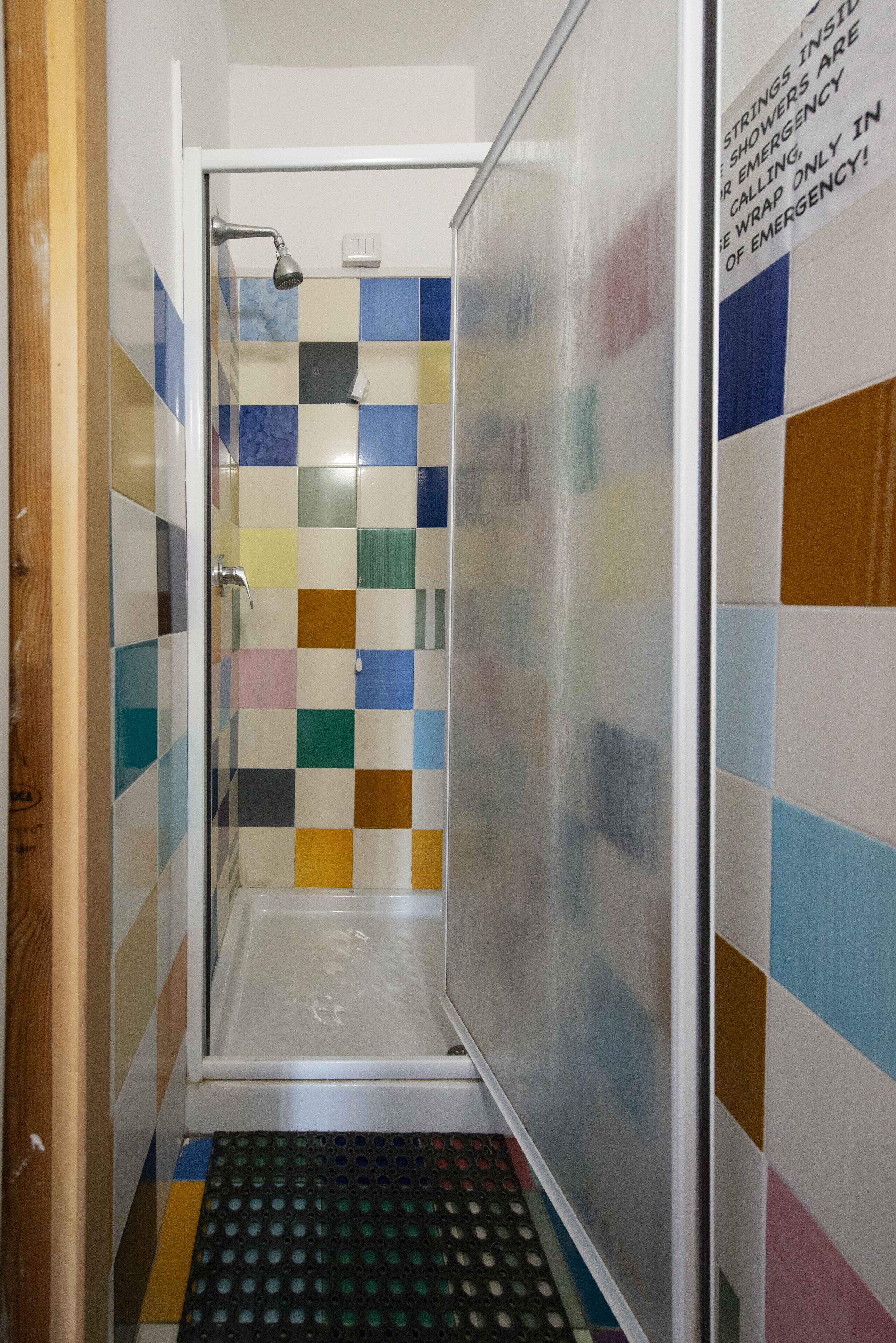 A shower with a checkered tile pattern and a warning sign about shower safety.