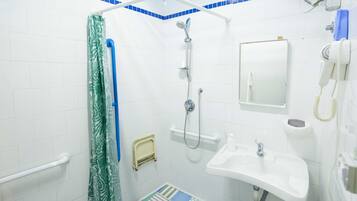 Un baño con ducha, lavamanos, espejo y teléfono.