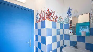 Une salle de bain avec des carreaux bleus et blancs formant un motif à carreaux, un lavabo blanc et une porte bleue.