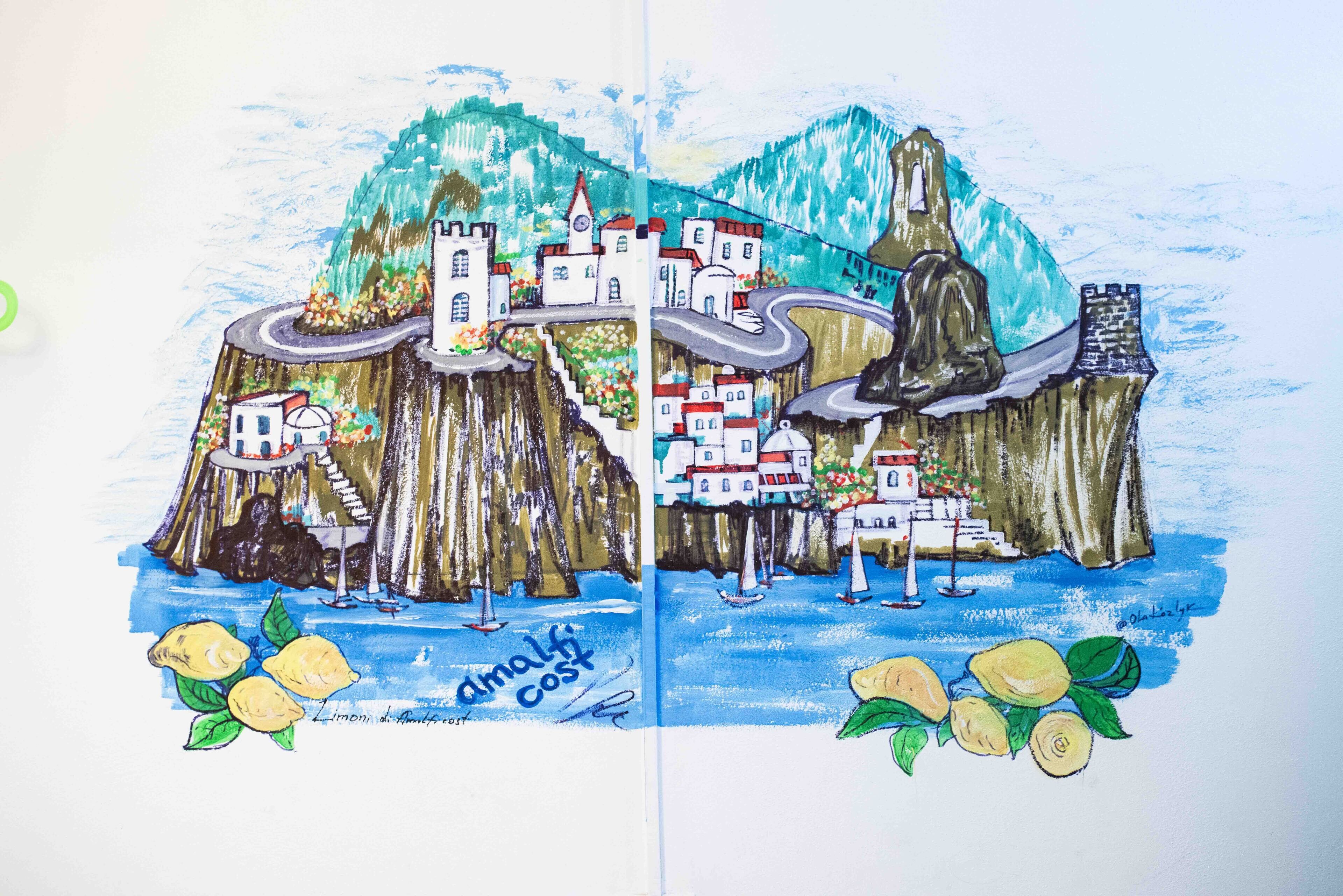 En farverig illustration af en kystby med bygninger, en kirke og en statue på en klippe.