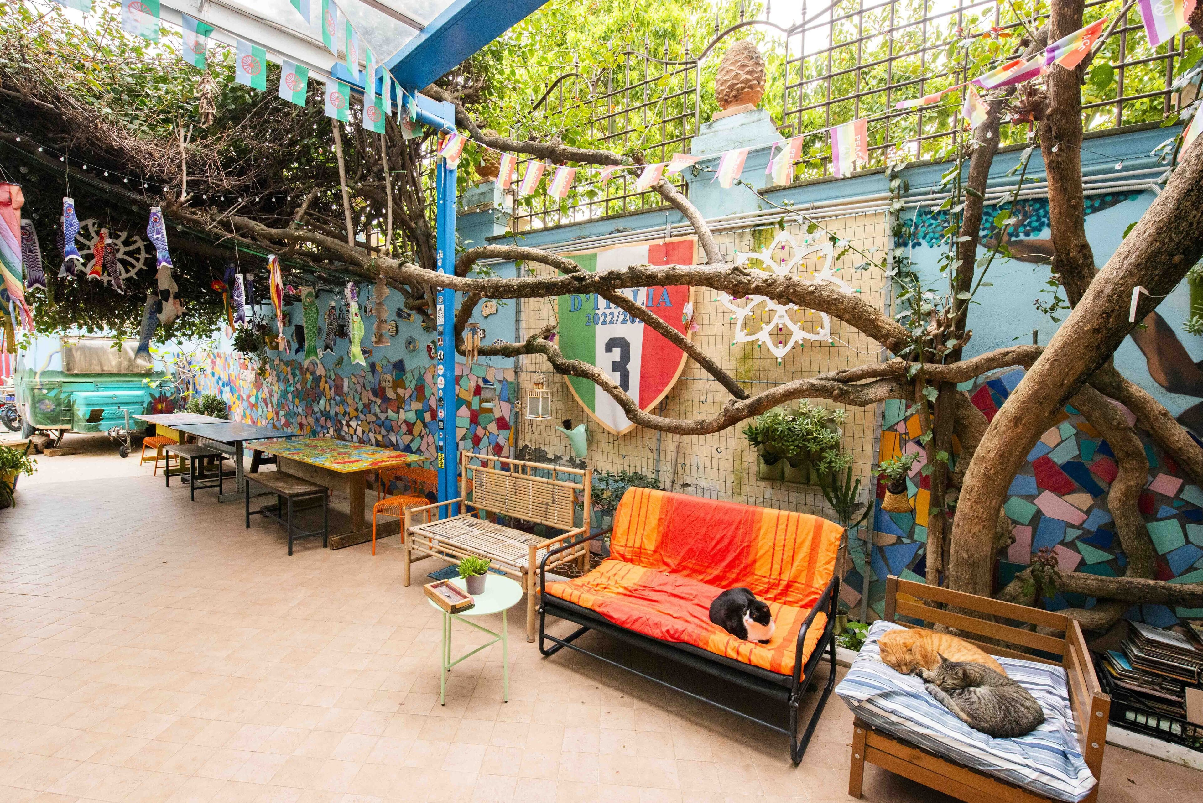 A cozy outdoor seating area with a sofa and a bench, surrounded by colorful murals and plants.