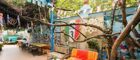 A cozy outdoor seating area with a sofa and a bench, surrounded by colorful murals and plants.