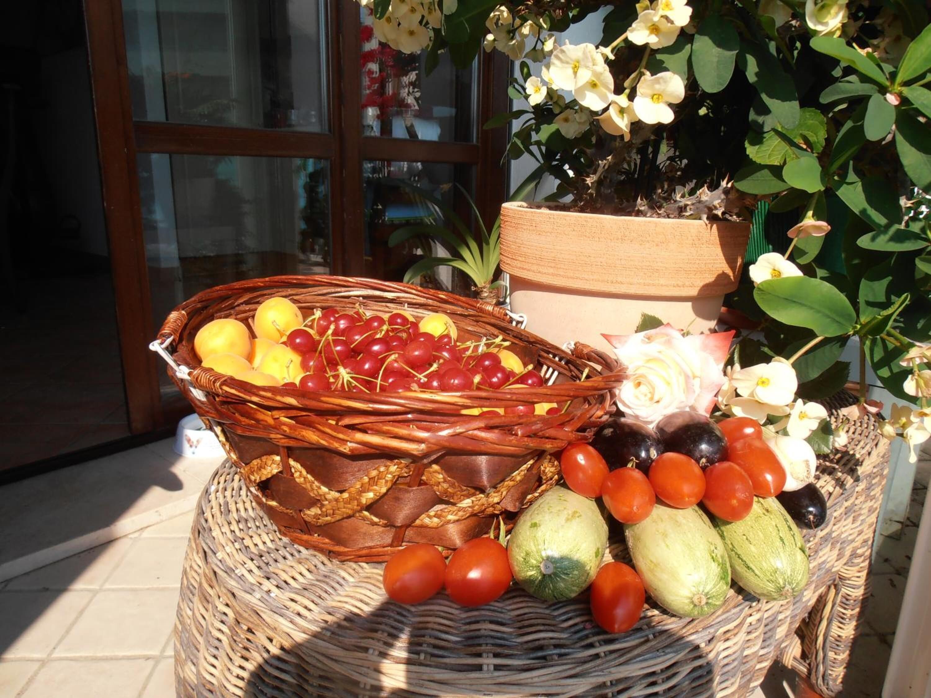 Un cesto di vimini pieno di frutta e verdura, posato su un pavimento piastrellato.