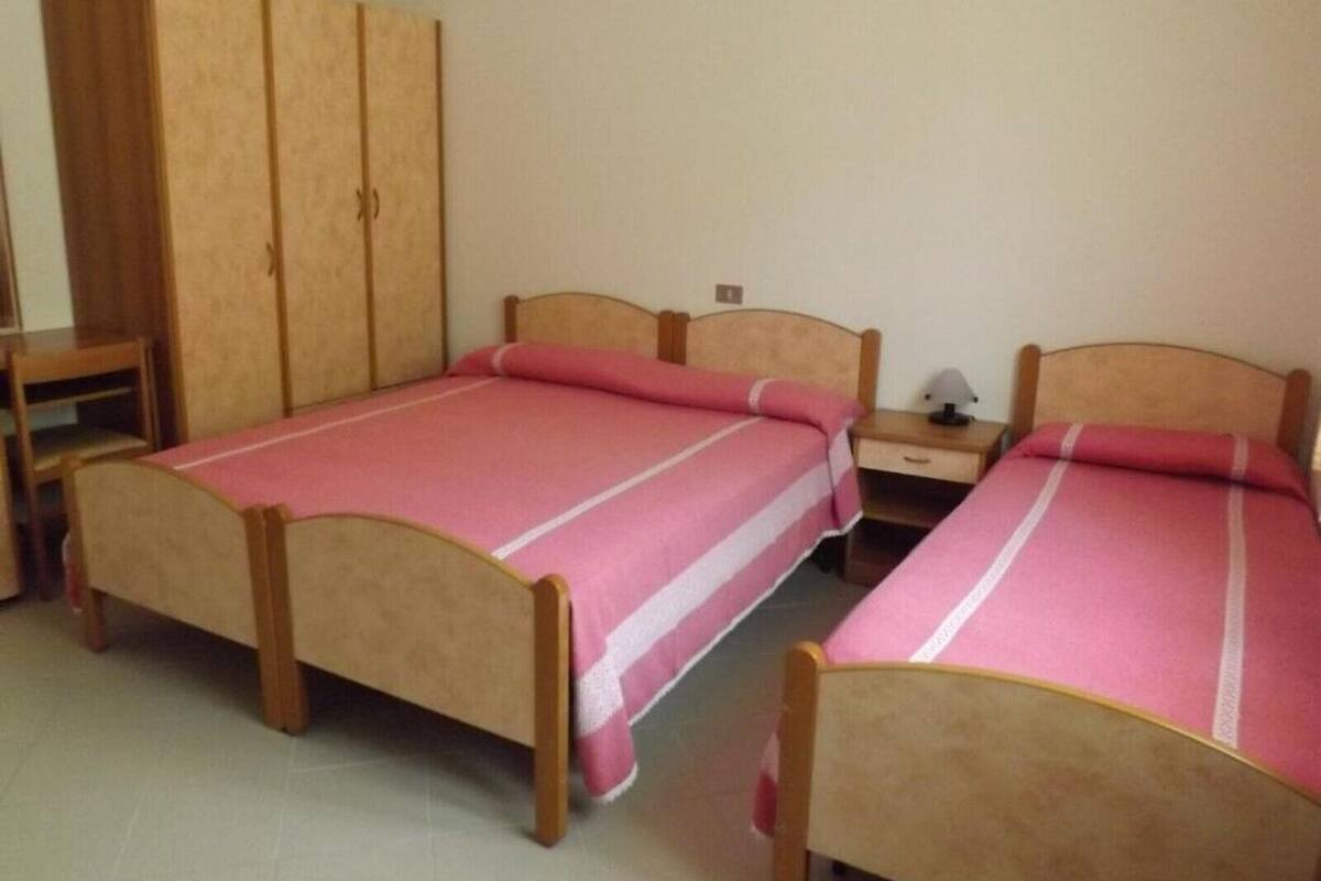 A room with two wooden beds, a wardrobe, and a small table.