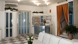 Un hall d’hôtel avec un sol à carreaux, un canapé blanc, un comptoir d’accueil et un escalier agrémenté de rideaux orange.