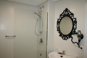 A bathroom with a glass-enclosed shower, a white sink, and a black ornate mirror. - Hotel Mirador del Ermitage (La Baneza)
