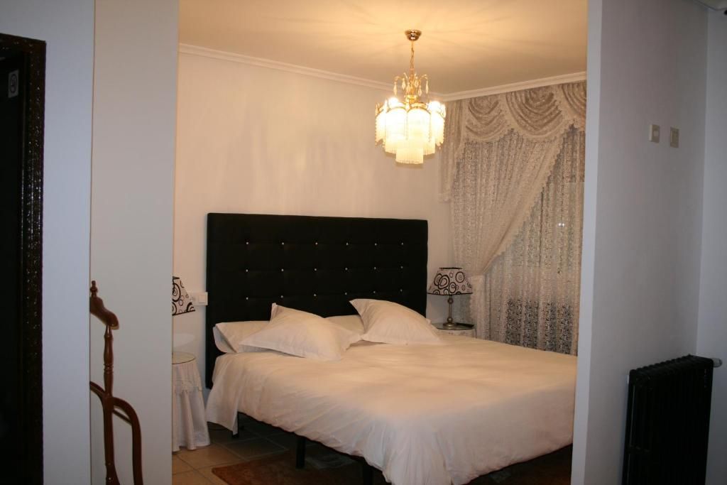 A bedroom with a large bed, a chandelier, and a curtain with a detailed pattern.