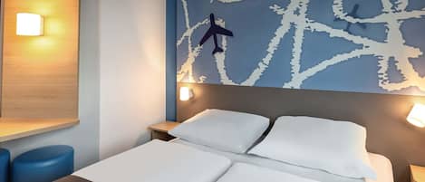 A hotel room with a bed, two bedside tables, a nightstand, and a wall with a map design.