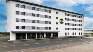 A modern B&B hotel with a white facade, multiple floors, and a parking lot in front. - B&B Hotel Frankfurt-Hahn Airport (Lautzenhausen)
