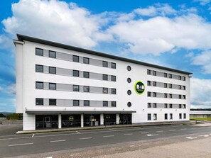A modern B&B hotel with a white facade, multiple floors, and a parking lot in front. - B&B Hotel Frankfurt-Hahn Airport (Lautzenhausen)