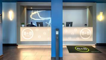 A reception area with a blue wall, a reception desk, and a digital screen.