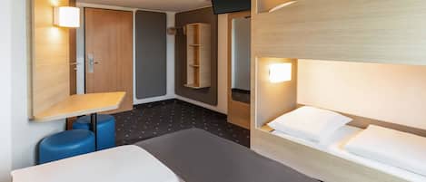 A hotel room with a bunk bed, a desk with a chair, a small table, and a wardrobe.
