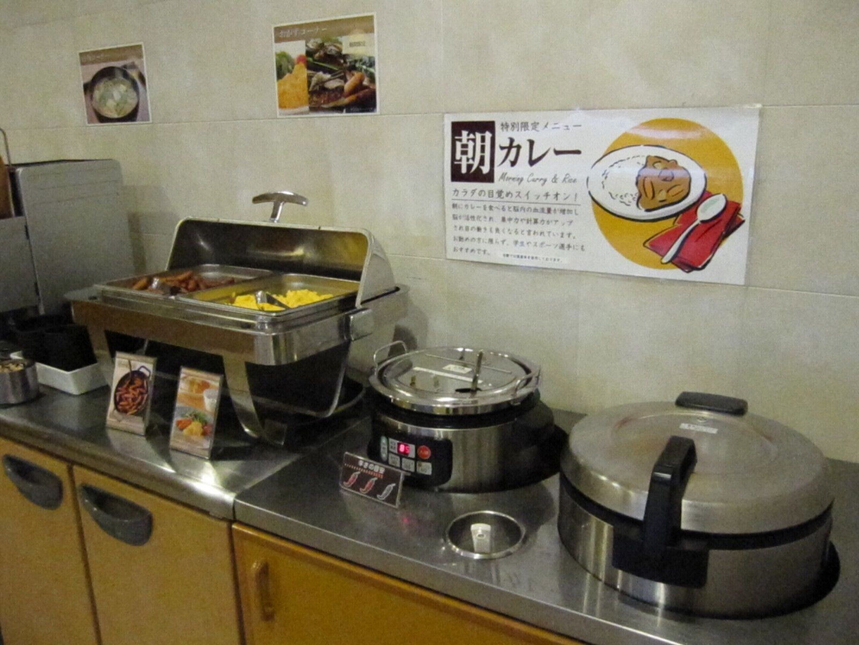 Una mesa de buffet con diferentes alimentos y una olla arrocera.