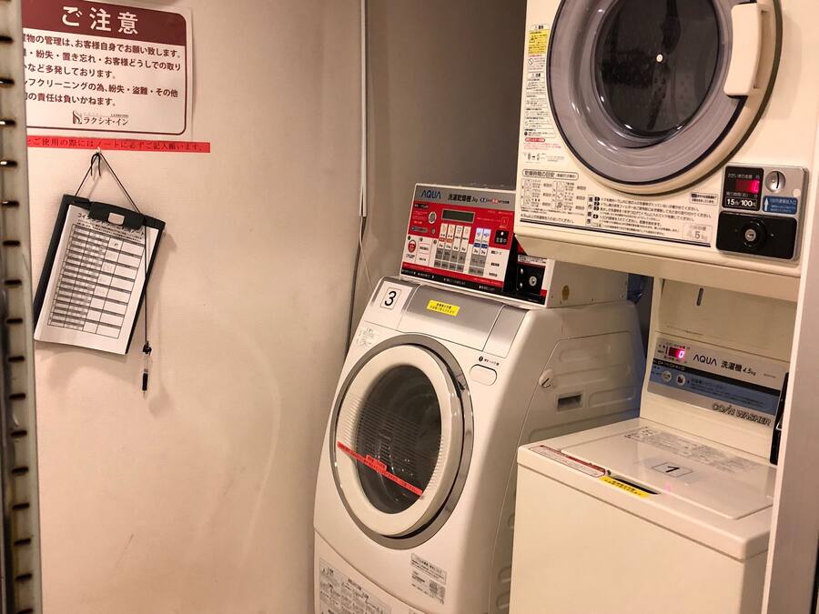 A laundry room with a wall clock, a sign with instructions, and a washing machine.