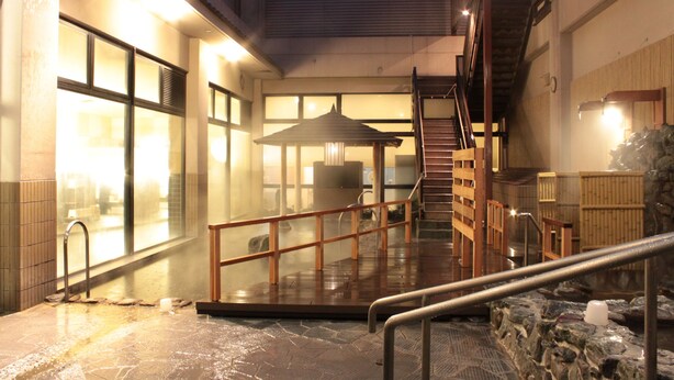 A heated outdoor area with a stone floor, a wooden staircase, and a glass enclosure with a view of the cityscape. - Laxio-Inn (Machida)