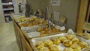 A buffet with various baked goods, including pastries and bread, arranged in wicker baskets. - Laxio-Inn (Machida)