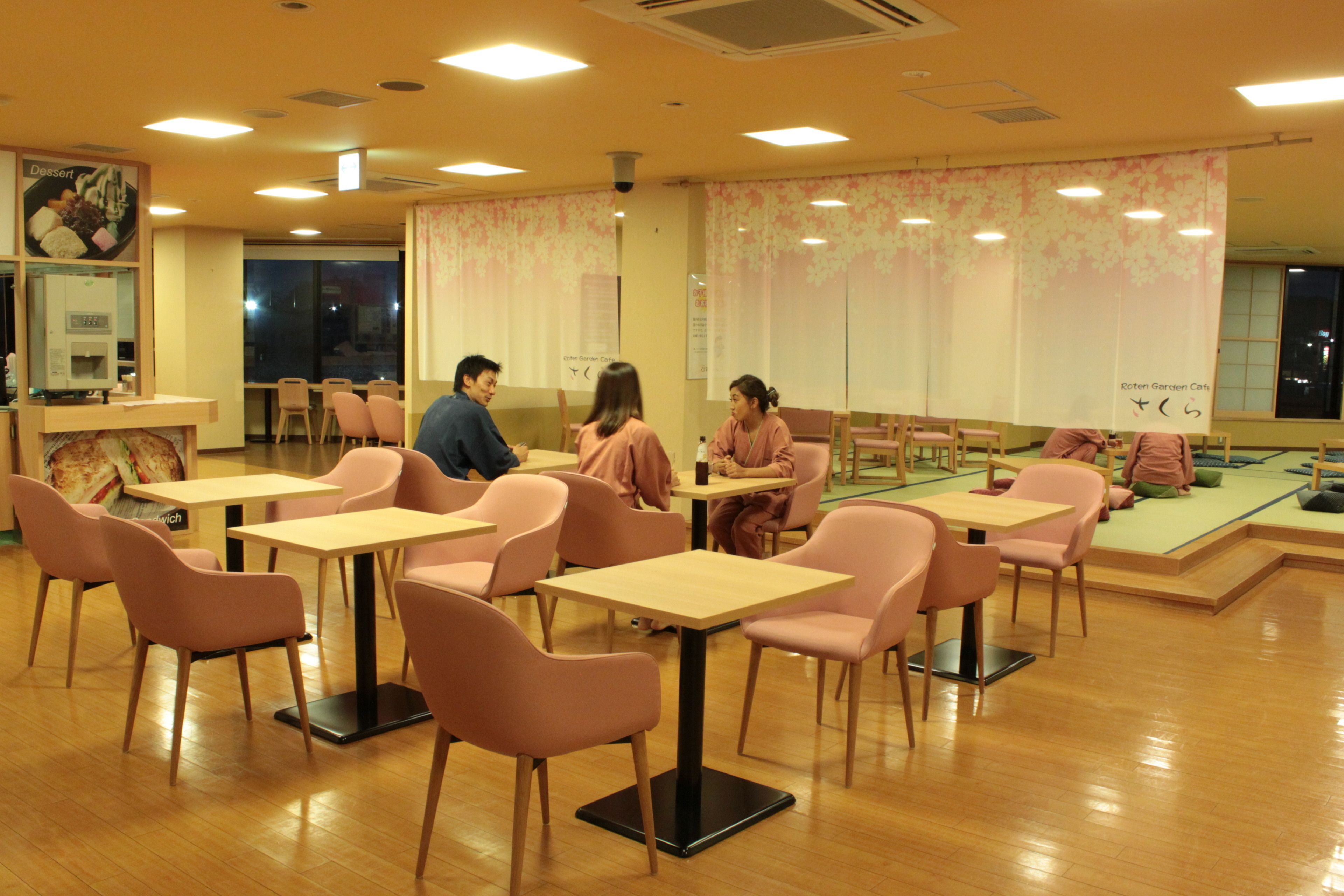 A dining area with tables and chairs, a dessert display, and a large window with a view.
