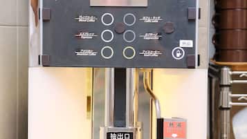 A coffee machine with multiple coffee options and a hand pressing a button.