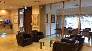 A lobby with leather seating, a reception desk, and framed artwork on the walls. - Laxio-Inn (Machida)