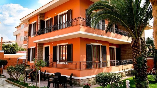 A two-story building with a balcony, outdoor seating, and a palm tree. - Villa Marogna Rooms and Breakfast (Alghero)