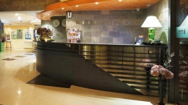 A reception desk with a curved design, a clock, and a lamp. - Grand Montana (Bansko)