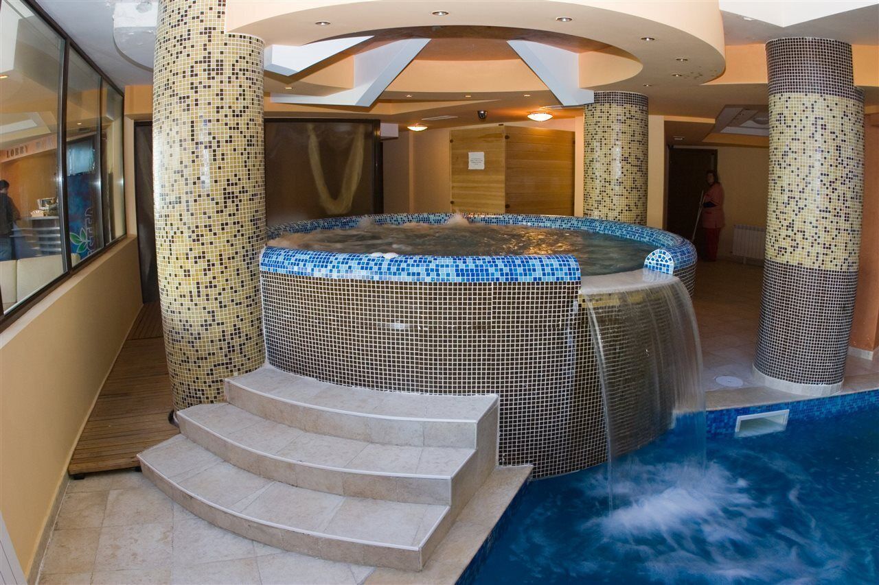 A hot tub with mosaic tile walls and steps leading up to it.