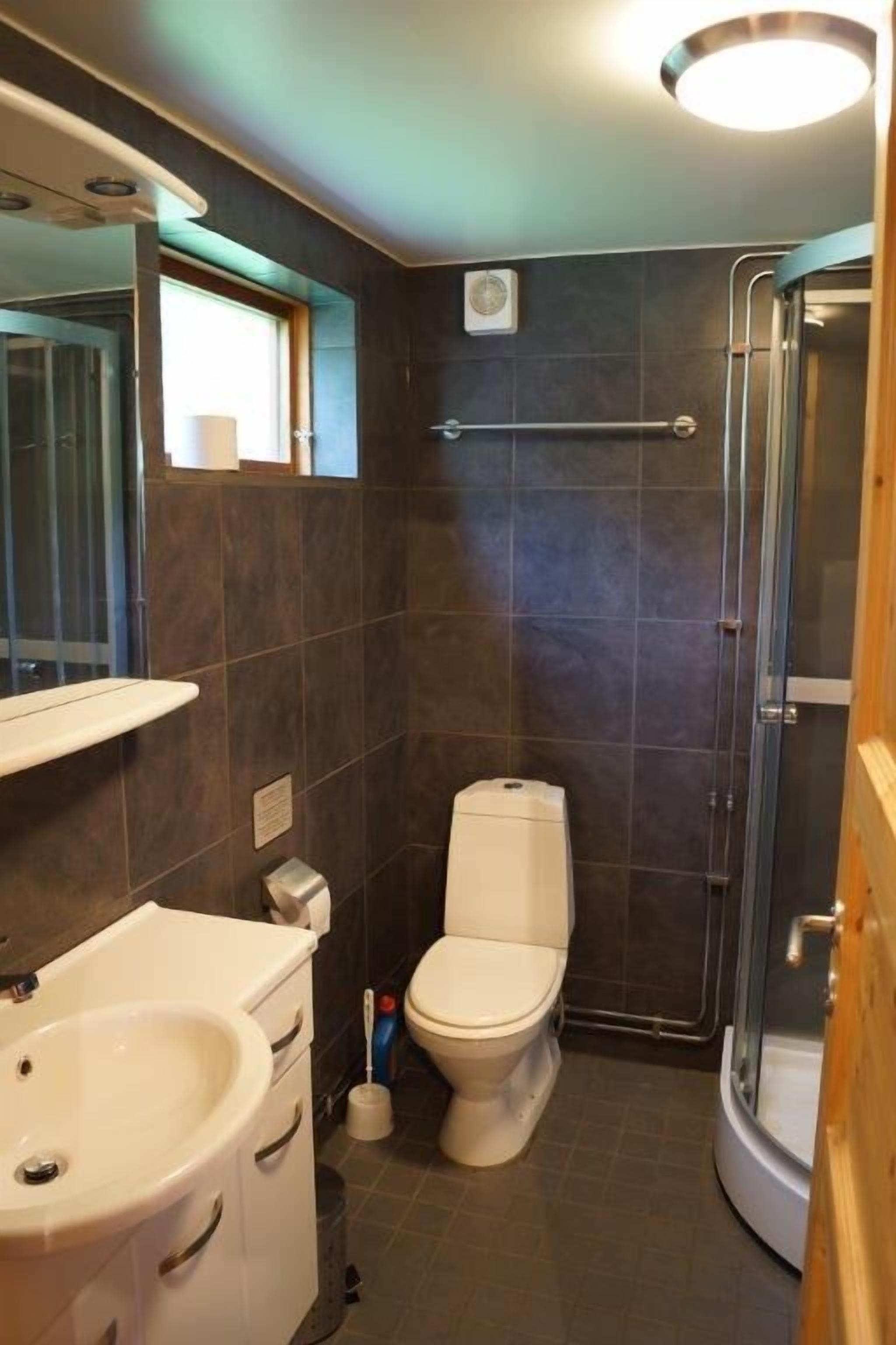 A compact bathroom with a toilet, sink, and shower.