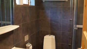 Un baño pequeño con inodoro, lavamanos y ducha.