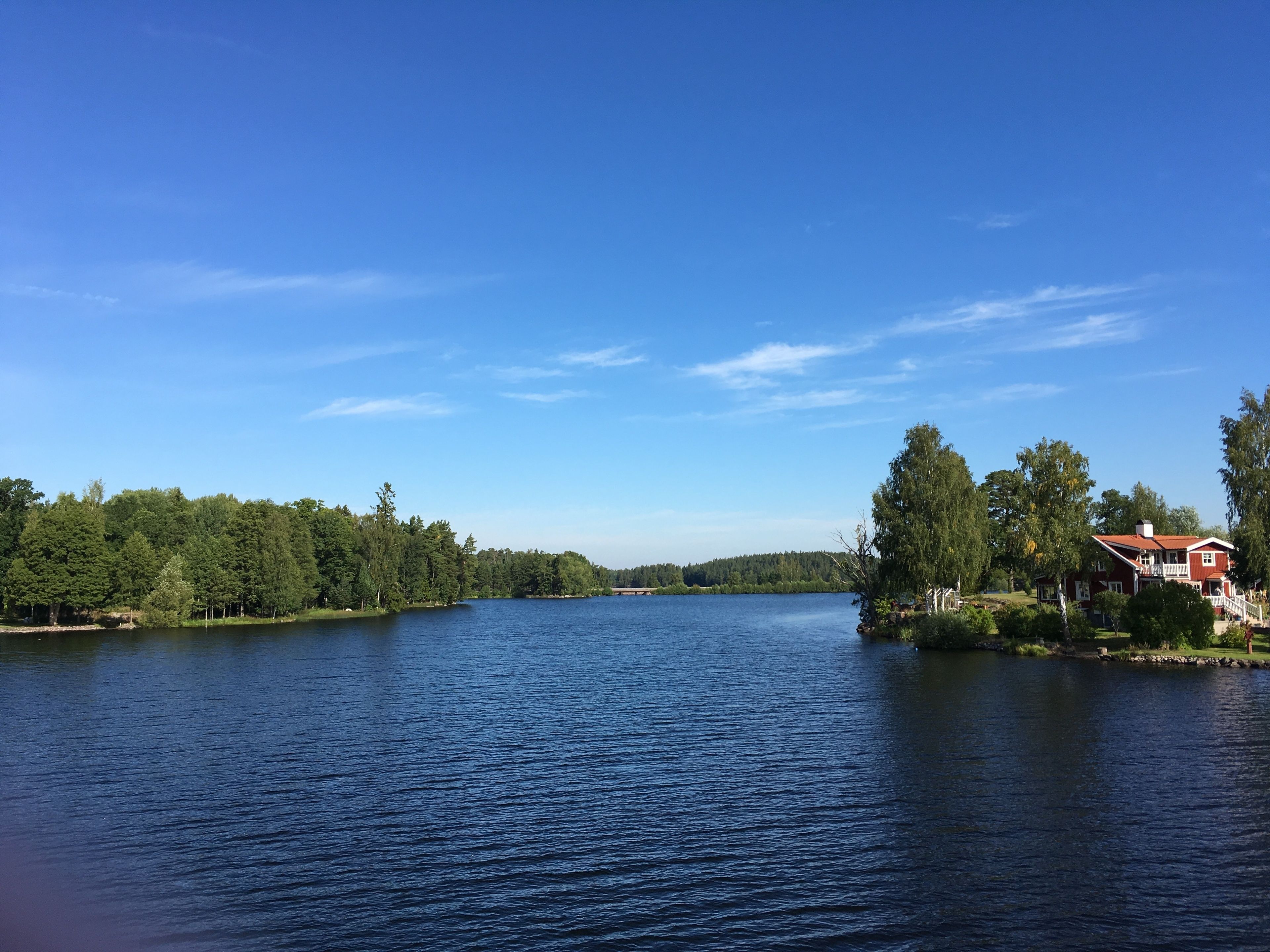 A lake with a red house on the right, surrounded by trees.