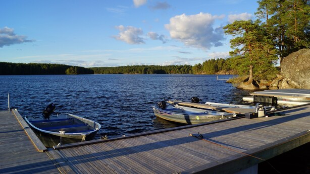 A wooden dock with several boats moored at the end. - Långsjön Stugor & Camping (Ankarsrum)