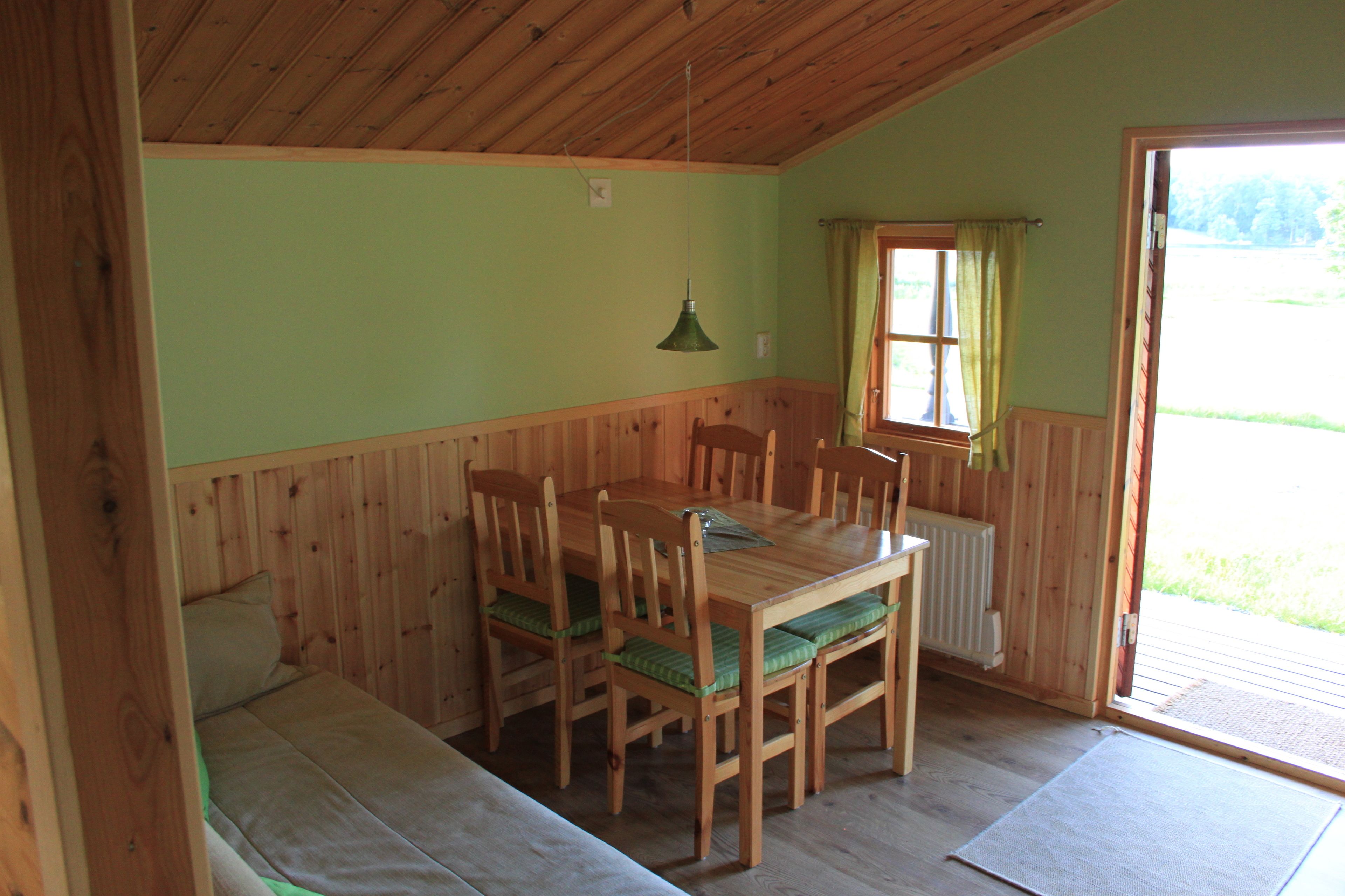A wooden dining table with chairs, a bench, a window with curtains, and a radiator.