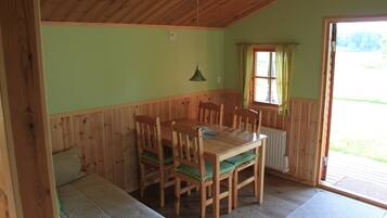 A wooden dining table with chairs, a bench, a window with curtains, and a radiator.