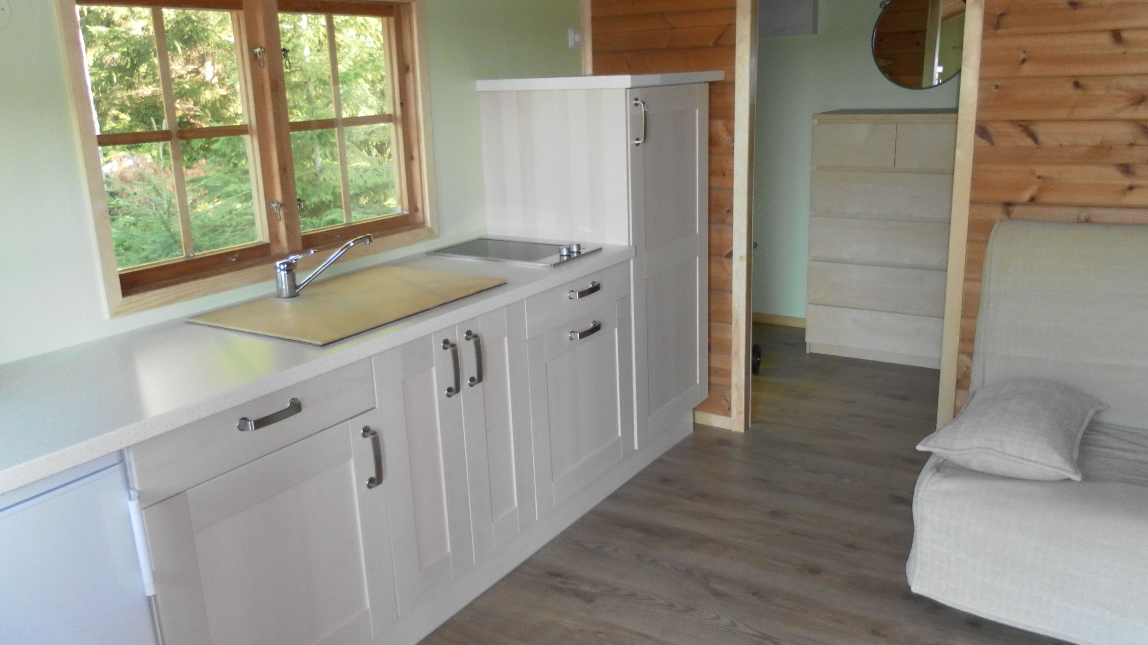 A compact kitchen with a window, wooden cabinets, and a sink.