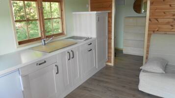 A compact kitchen with a window, wooden cabinets, and a sink.