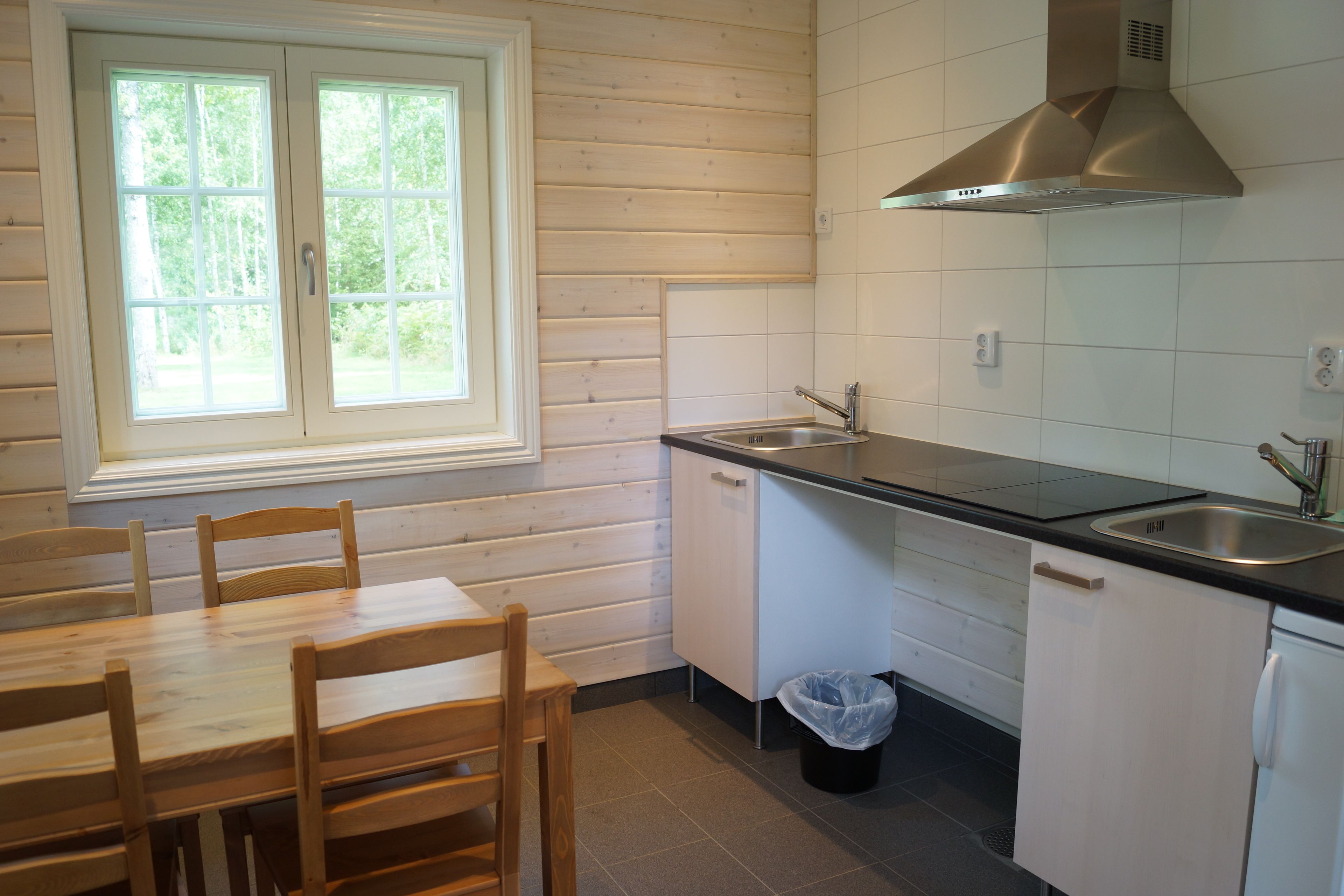 Una cucina funzionale con tavolo e sedie in legno, una finestra, un lavandino e una lavastoviglie.