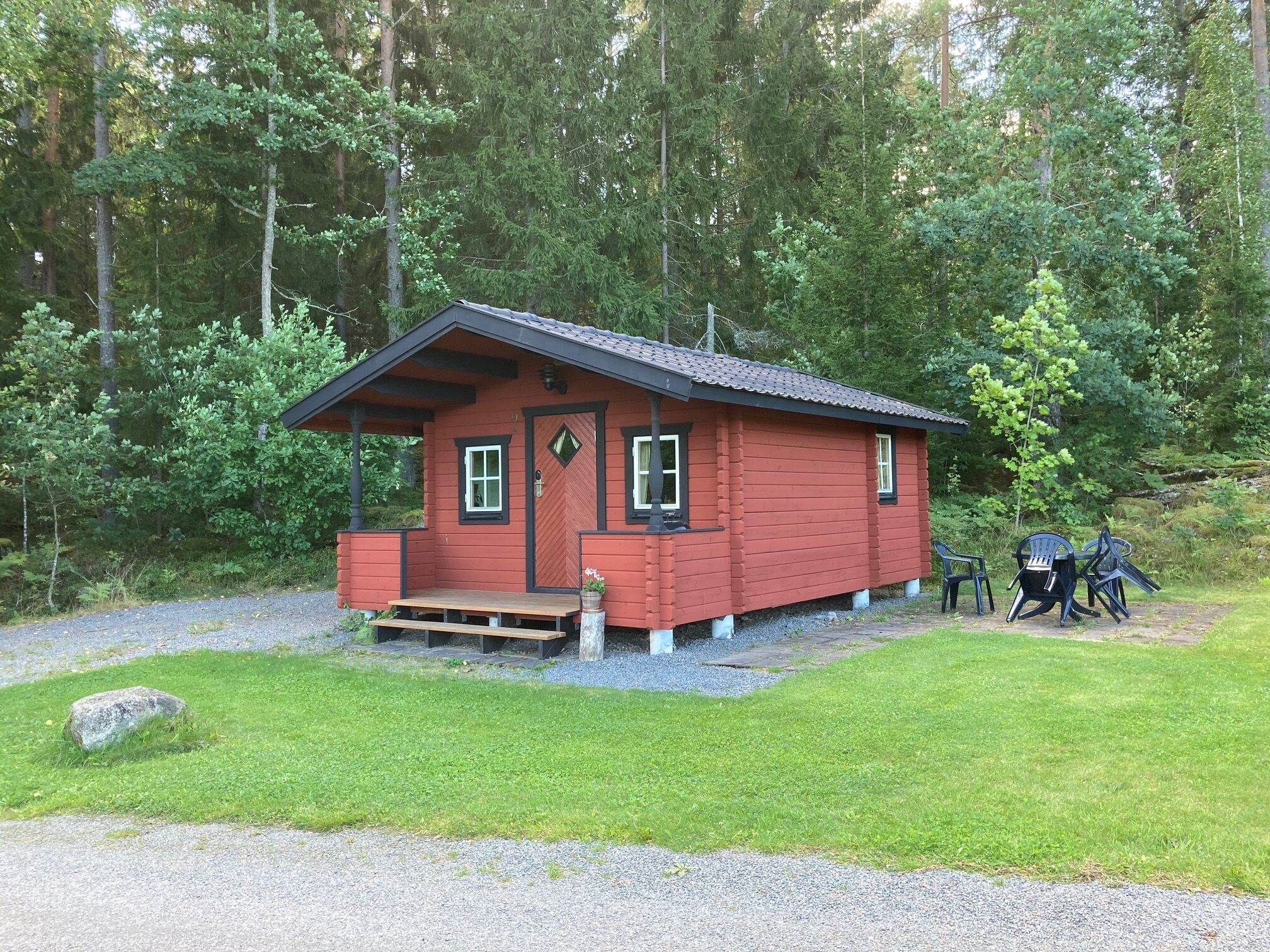 Una piccola baita rossa con un portico e un vialetto sterrato che vi conduce.
