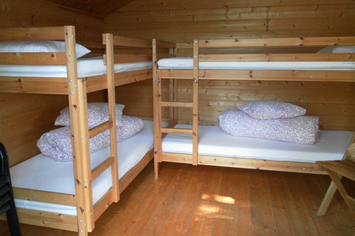 A wooden bunk bed room with three bunk beds, each with a pillow and a mattress.
