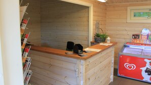A wooden interior with a reception desk, a freezer with a heart logo, and a wall-mounted plant. - Långsjön Stugor & Camping (Ankarsrum)
