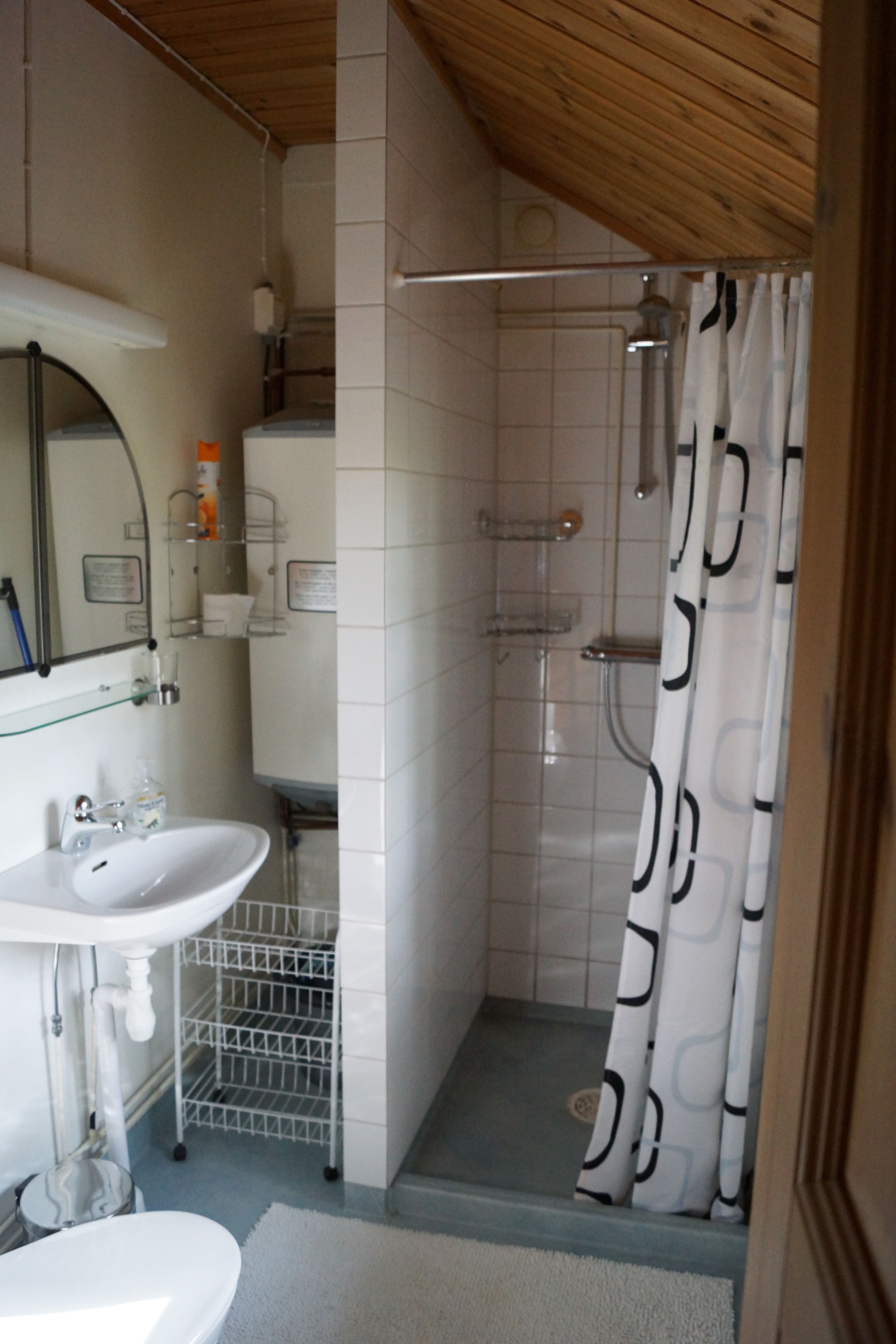 A bathroom with a sink, mirror, shower, and a towel rack.