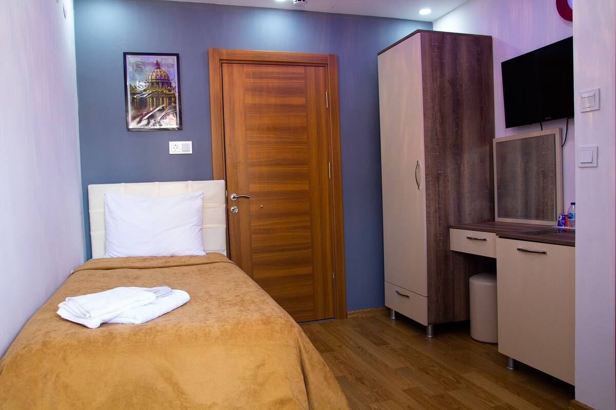 Une chambre d’hôtel avec un lit, une armoire, une télévision et un tableau au mur.